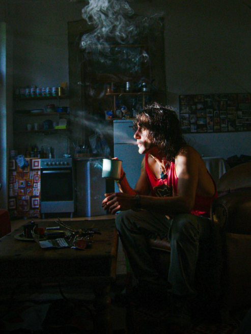 homme dans son salon, fumant une cigarette et buvant un café