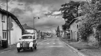 photo noir et blanc depuis une voiture sur une route avec une ancienne voiture en croisement