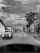 photo noir et blanc depuis une voiture sur une route avec une ancienne voiture en croisement