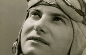 Photographie en noir et blanc d'Hélène Boucher, grande figure de l'aviation, regardant vers le ciel