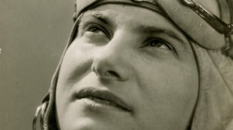 Photographie en noir et blanc d'Hélène Boucher, grande figure de l'aviation, regardant vers le ciel