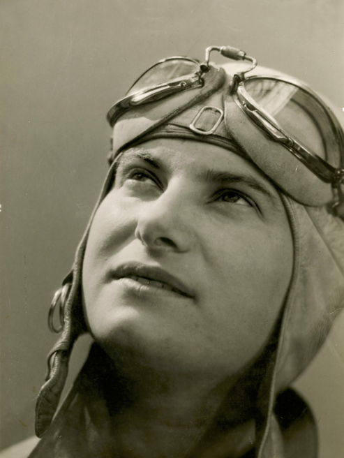 Photographie en noir et blanc d'Hélène Boucher, grande figure de l'aviation, regardant vers le ciel